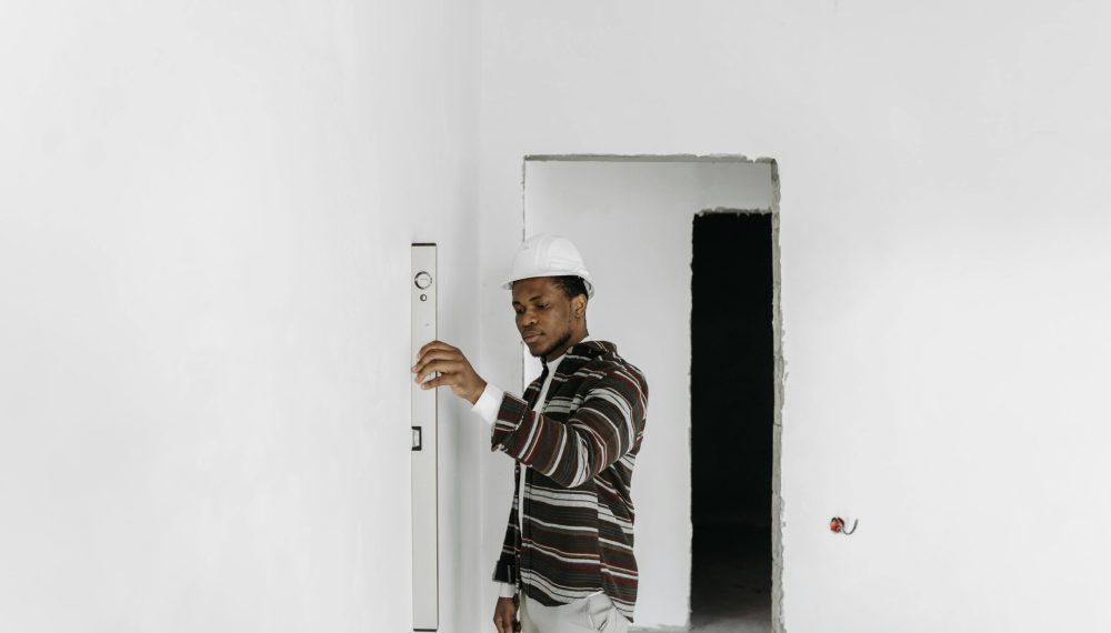 Architect wearing hard hat checks wall alignment in a renovation project.